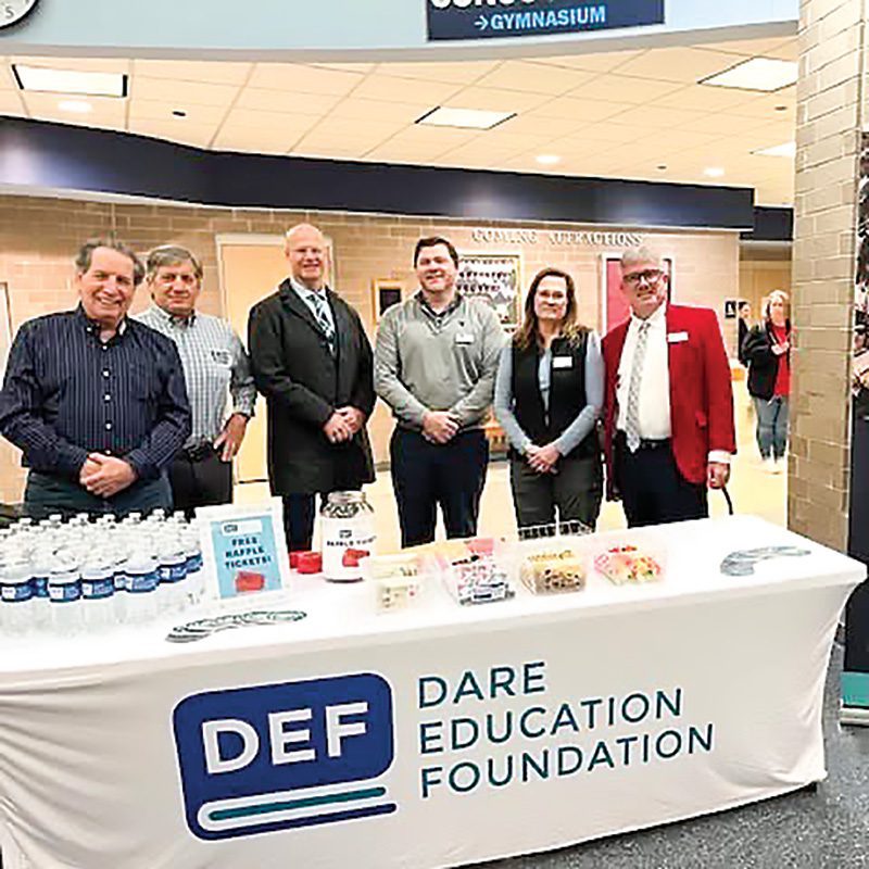 Below: Ben Sproul joins Dare Education Foundation board members at First Flight High School to meet with local teachers as they arrive for a work day. The long-time local is well known from his time as a business owner, school board member and mayor of Kill Devil Hills, and now serves as Executive Director of DEF.