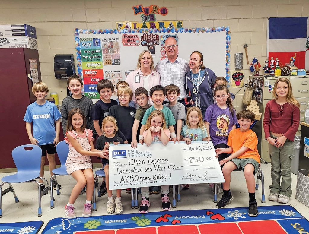 Above: Kitty Hawk Elementary School Media Center Coordinator Ellen Bryson (right) shows off a donation check for a project to celebrate the 250th birthday of America. New Dare Education Foundation Executive Director Ben Sproul said visiting schools to hand out money to support local students is a major highlight of the job.