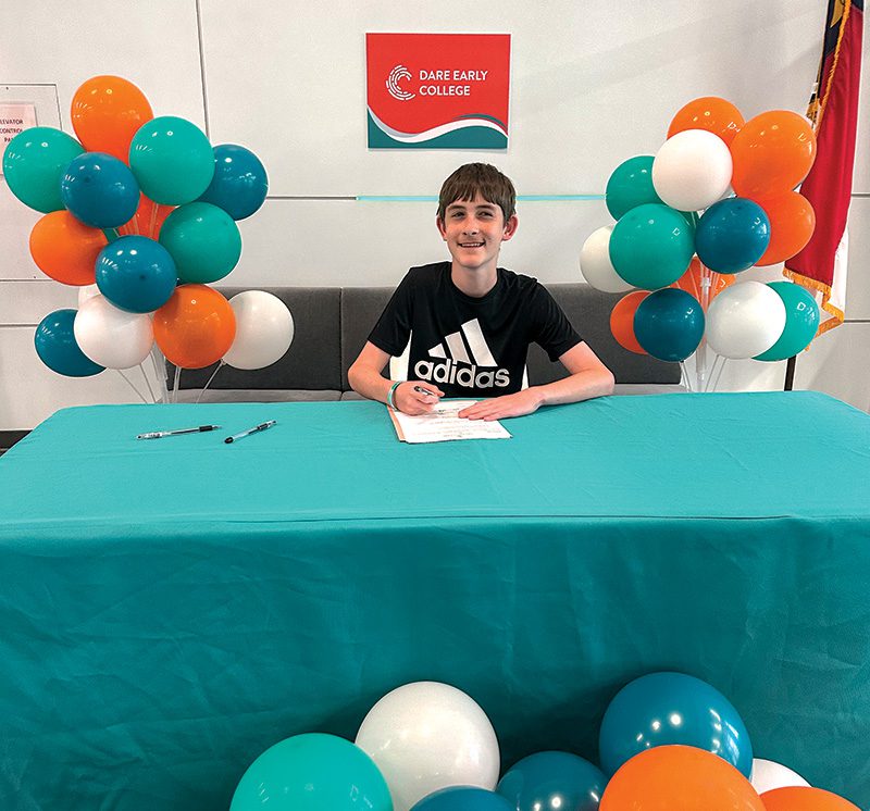 Dylan Wood, graduate of First Flight Middle School, signs his commitment to attend Dare Early College. Photo by Ann Wood.