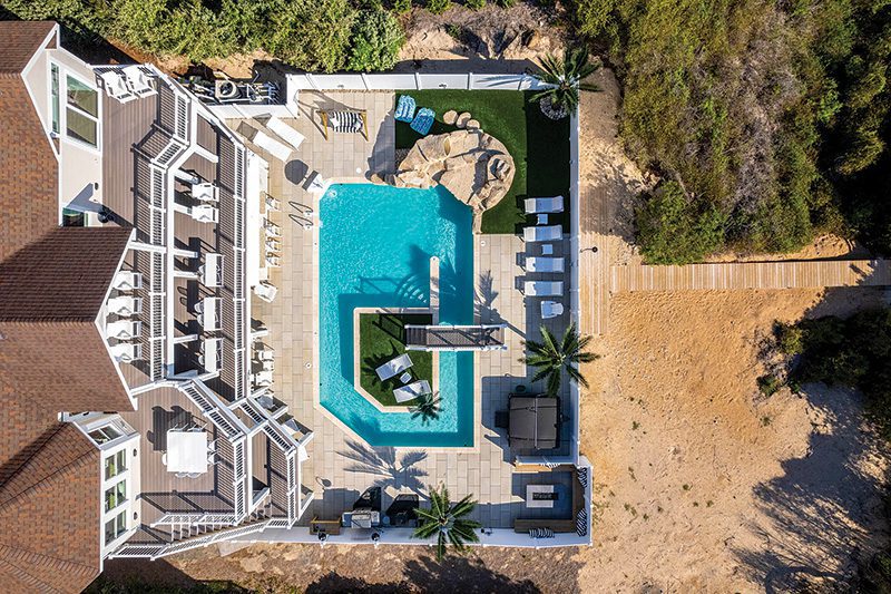 From The Palm’s elevated decks to the pool’s central gathering point, the design creates a natural flow that keeps guests moving easily between spaces. Image from Carolina Designs.