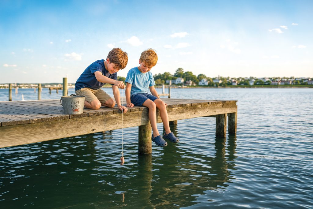 2 boys fishing for crabs off a dock in summer time